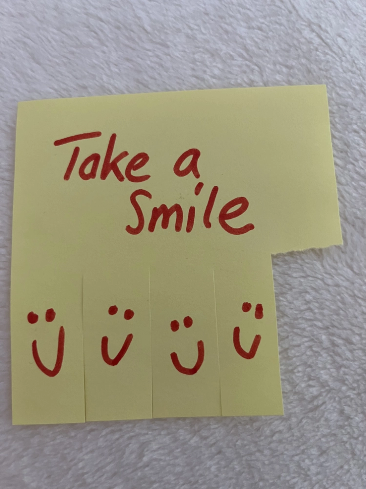 Post it mit Text "take a smile" in roter Schrift.